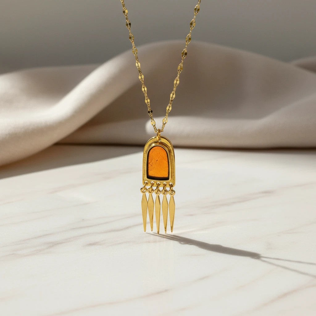 Elephantina.gr gold-tone stainless steel necklace with amber-colored enamel pendant and dangling geometric charms.