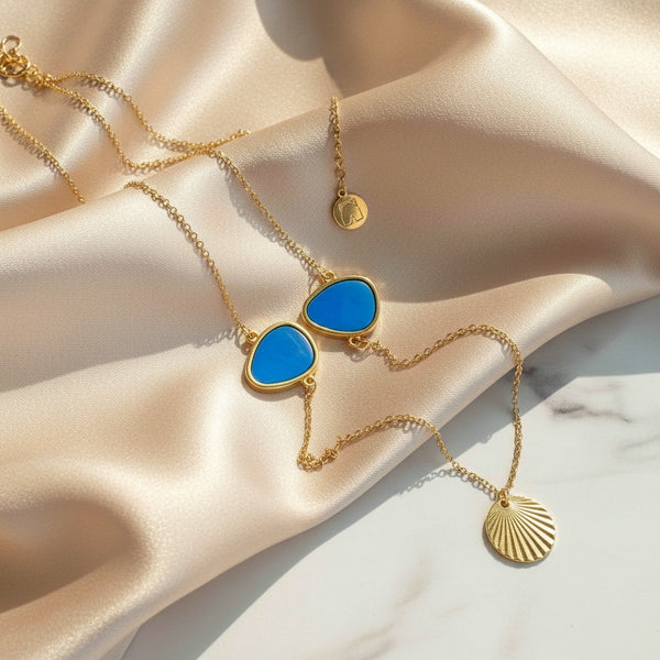 Elephantina.gr gold-tone necklace with two blue enamel geometric pendants and a sunburst charm.