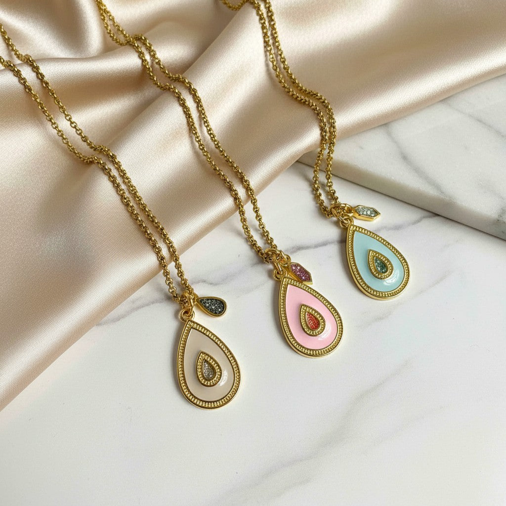 elephantina.gr gold chain necklace with teardrop pendant in pastel pink, white, and blue enamel with glitter accents.