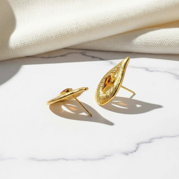 elephantina.gr gold leaf-shaped brass earrings with textured finish and brown enamel detail on a marble surface
