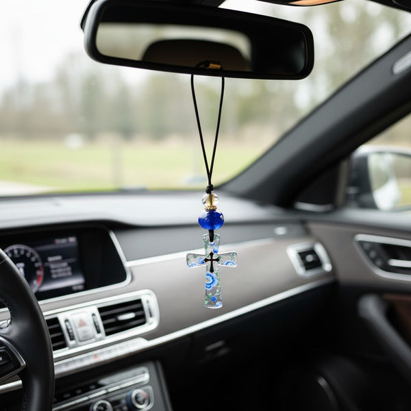 Clear glass cross pendant with blue floral design, black cord, blue bead, and gold accents. elephantina.gr