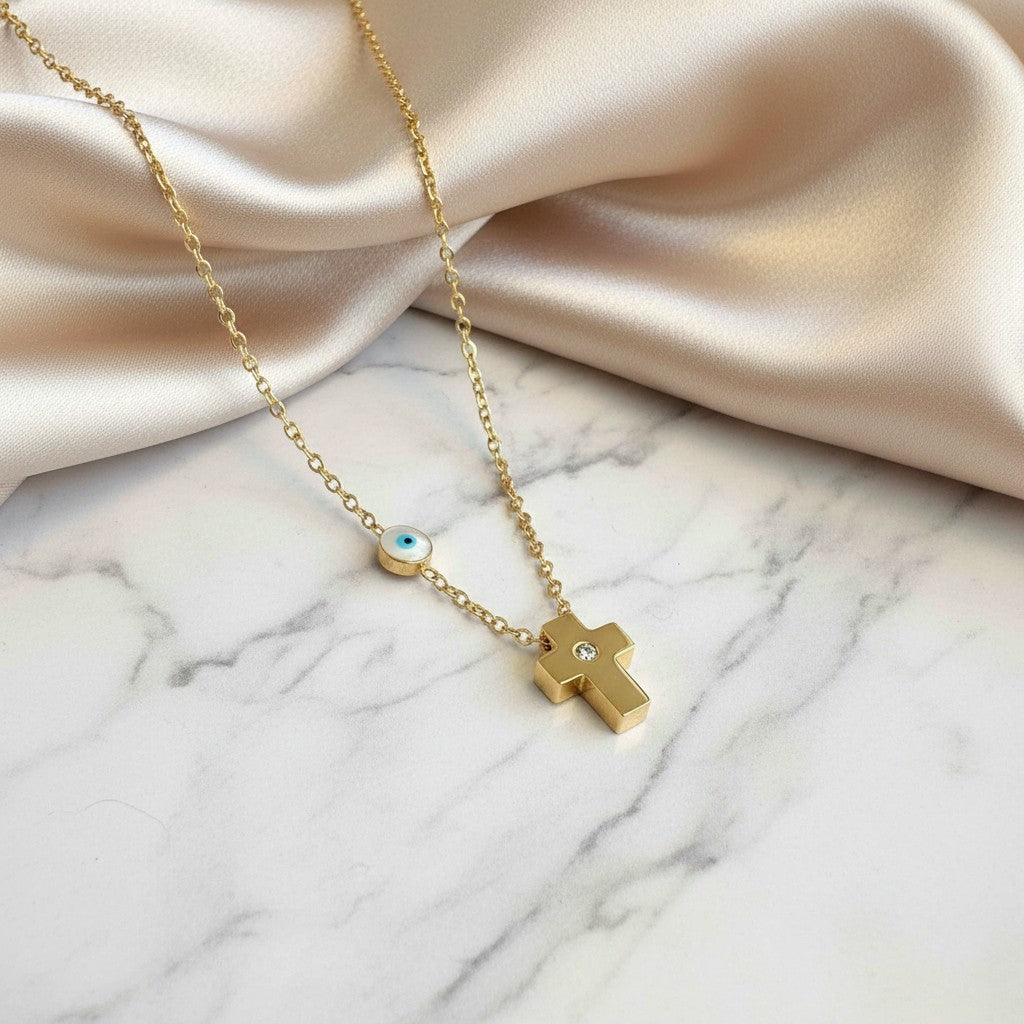 elephantina.gr gold-plated steel cross necklace with a white mother-of-pearl evil eye charm on a delicate chain.