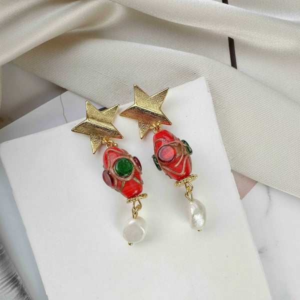 elephantina.gr 24k gold-plated star stud earrings with red glass beads, green accents, and irregular pearl drops.